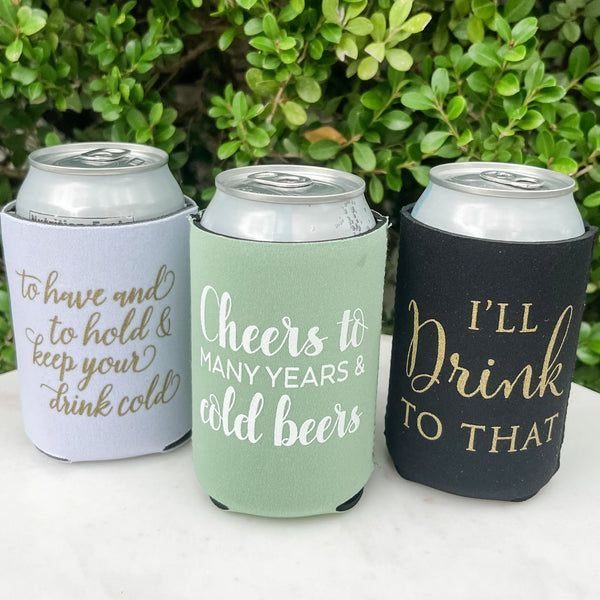 Three colorful neoprene can coolers with gold text sitting on a white surface.