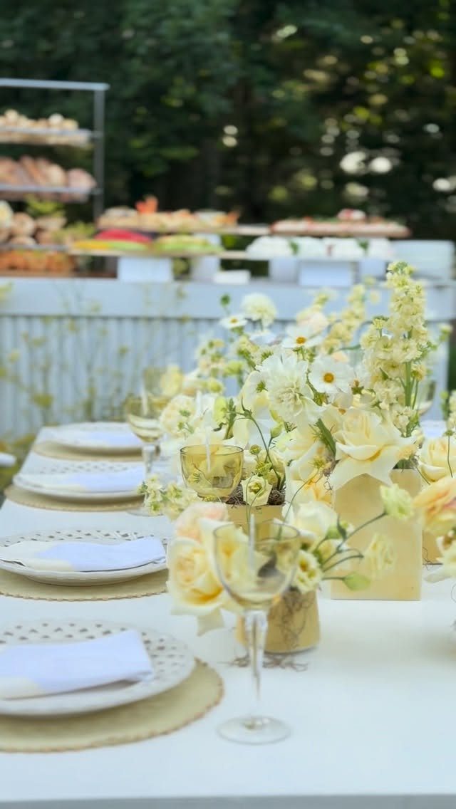 White and yellow floral centerpiece on a white wedding table with gold accents.