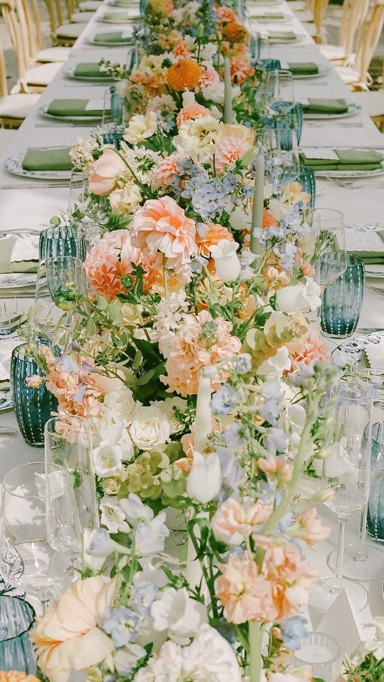 Floral table runner with peach and light blue flowers and blue glassware.