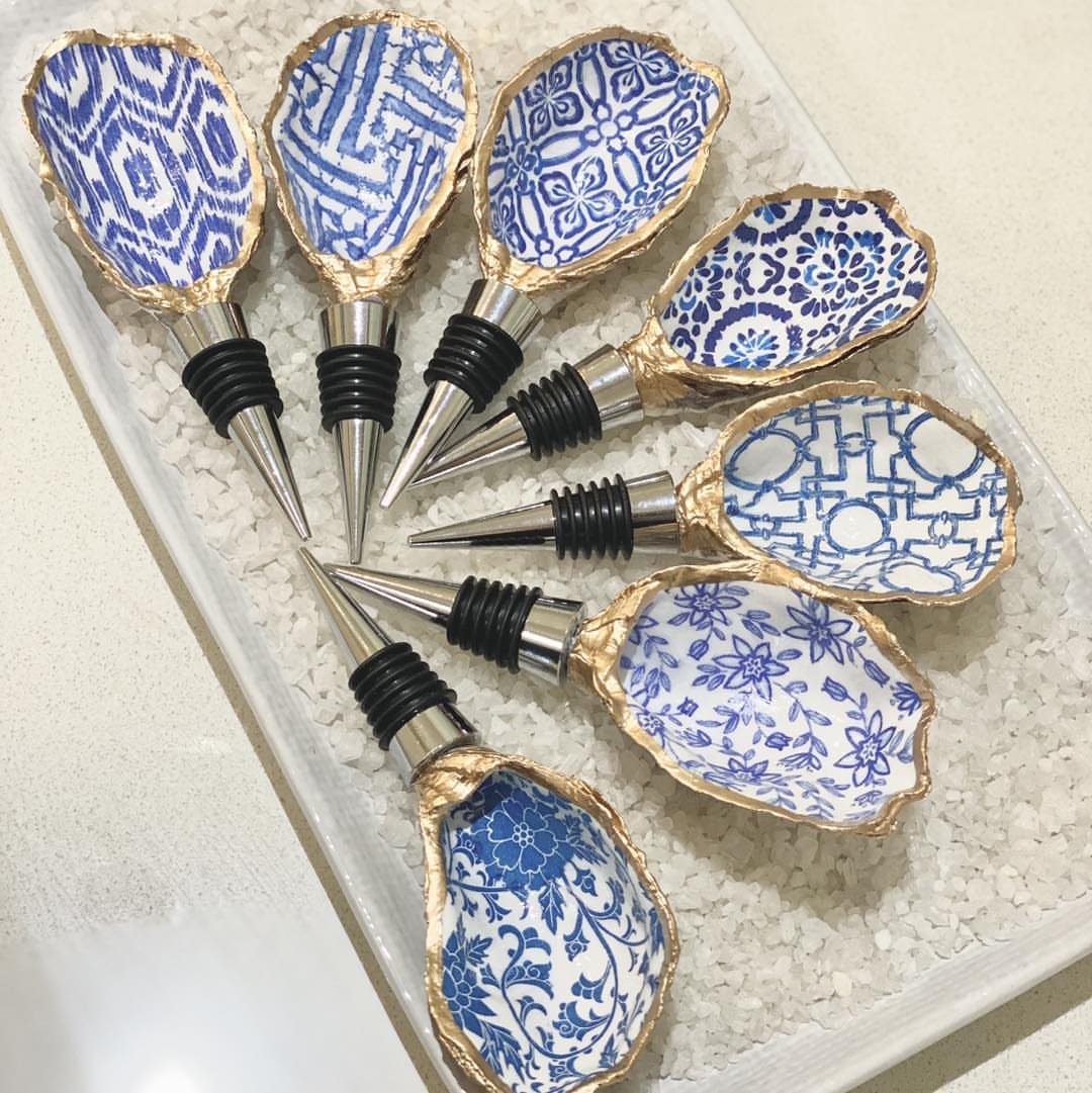 Shell-shaped bottle stoppers with blue and white patterns on a bed of white pebbles