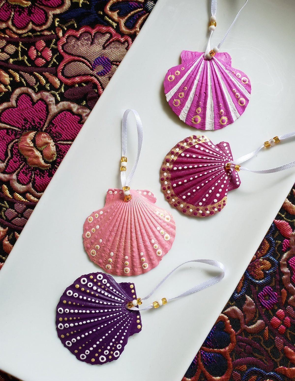 Painted scallop shell ornaments with white dots and ribbons on a white plate