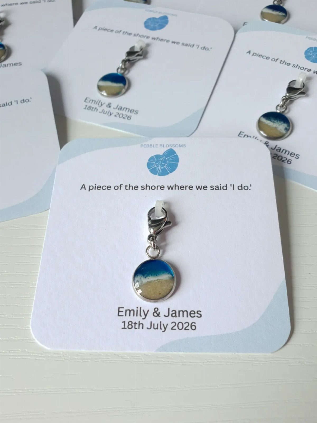 Circular beach scene charms attached to personalized white wedding favor cards.