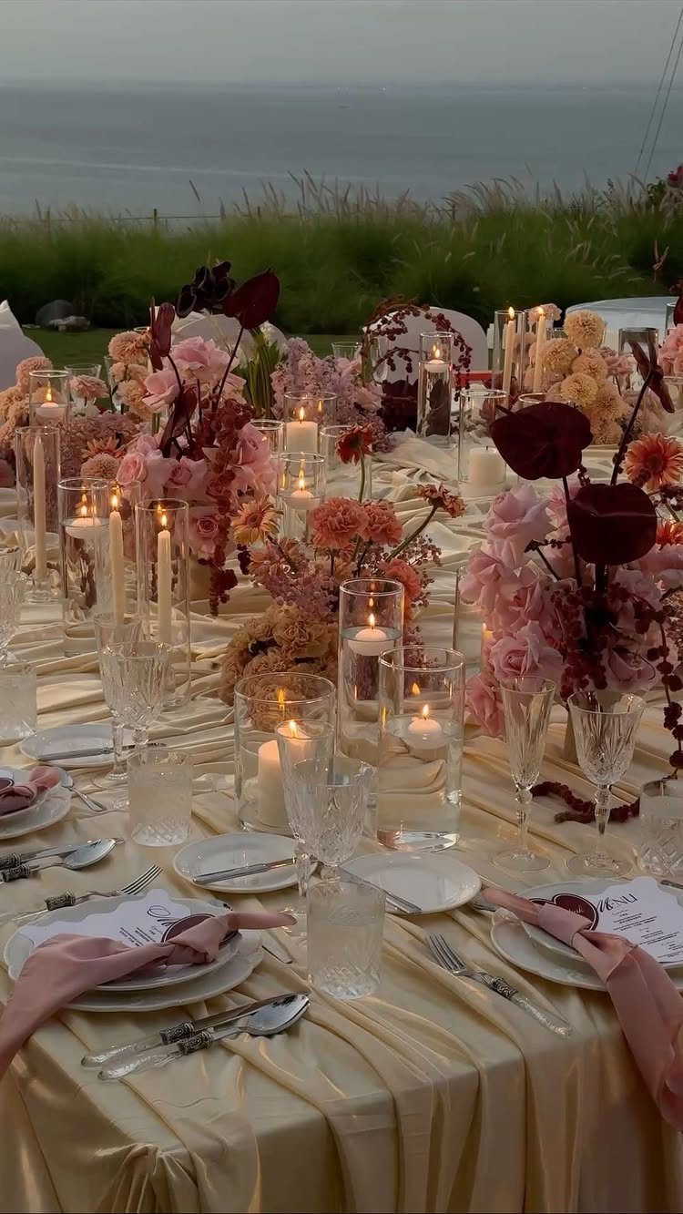 Champagne wedding table with pink flowers and candles overlooking the ocean beach.