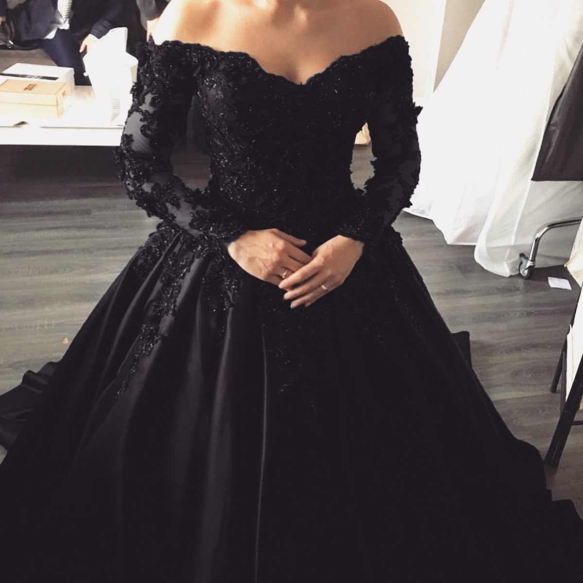 Off-the-shoulder black bridal gown with lace sleeves and a full voluminous skirt