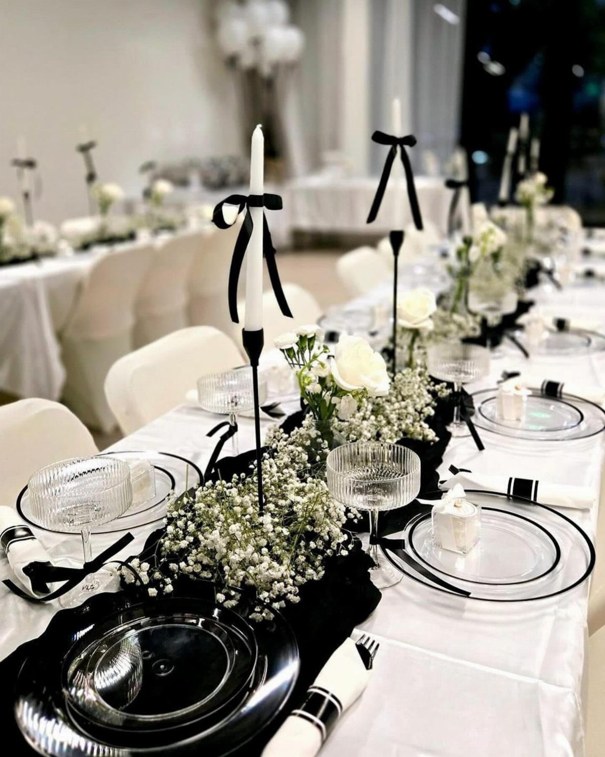 Wedding table setting with black runner, white flowers, and black candle holders.