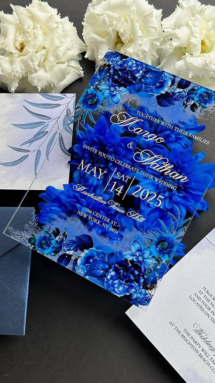 Blue floral wedding invitation with matching stationery and white carnations on dark background