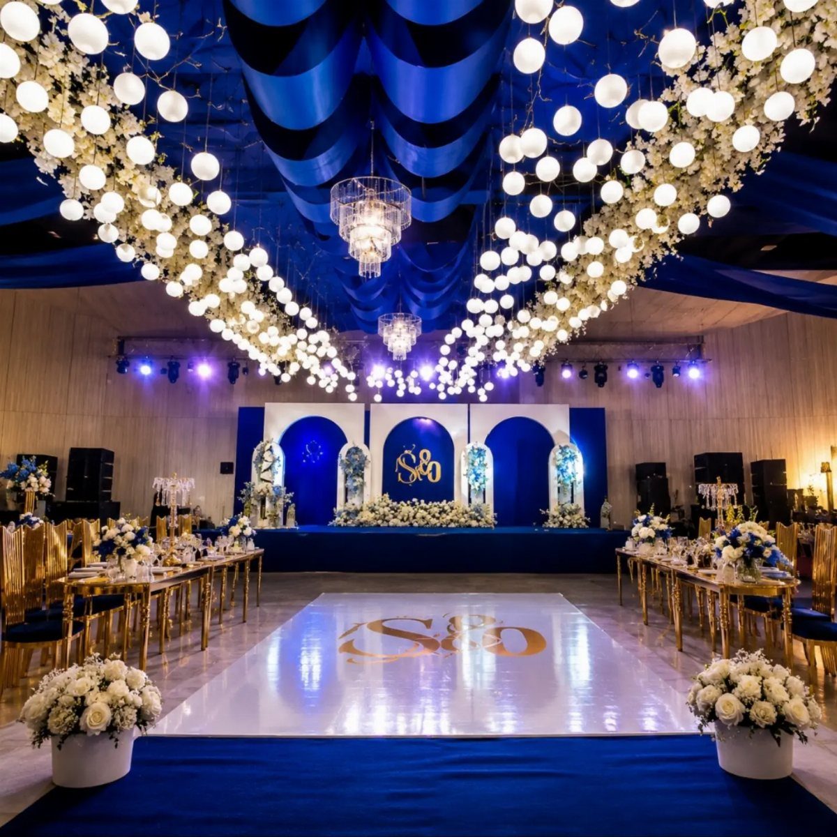 Royal blue and gold wedding reception hall with white floral ceiling installations.