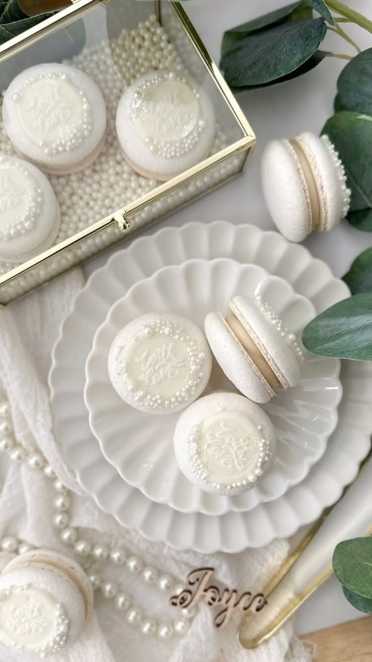 White macarons in a glass box and on scalloped plates with pearls.