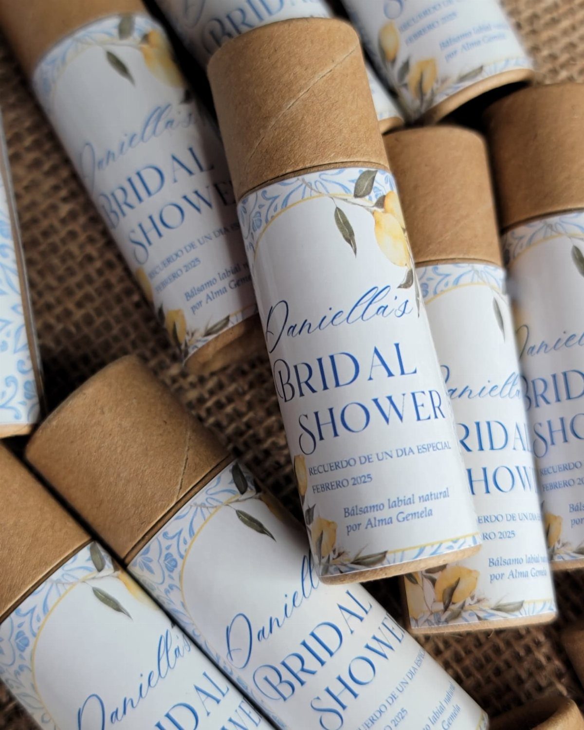 Custom lip balm tubes with bridal shower labels and lemon designs on burlap.