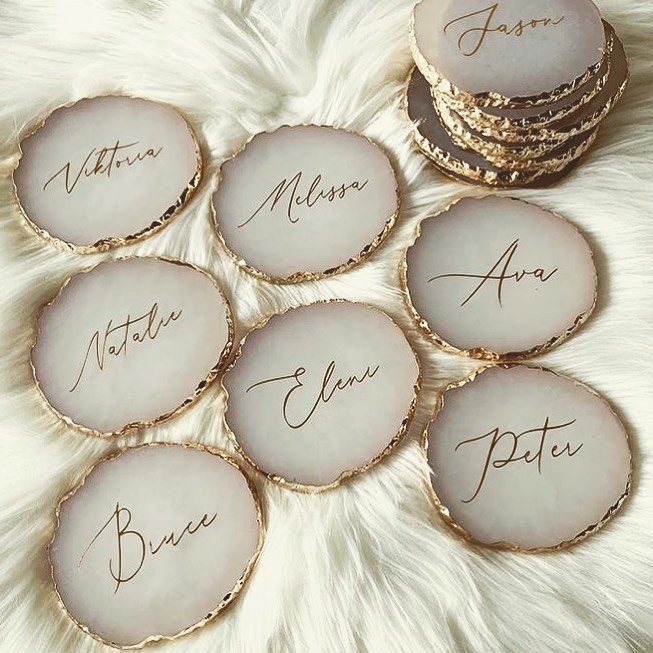 White agate coasters with gold edges and personalized names on white faux fur.