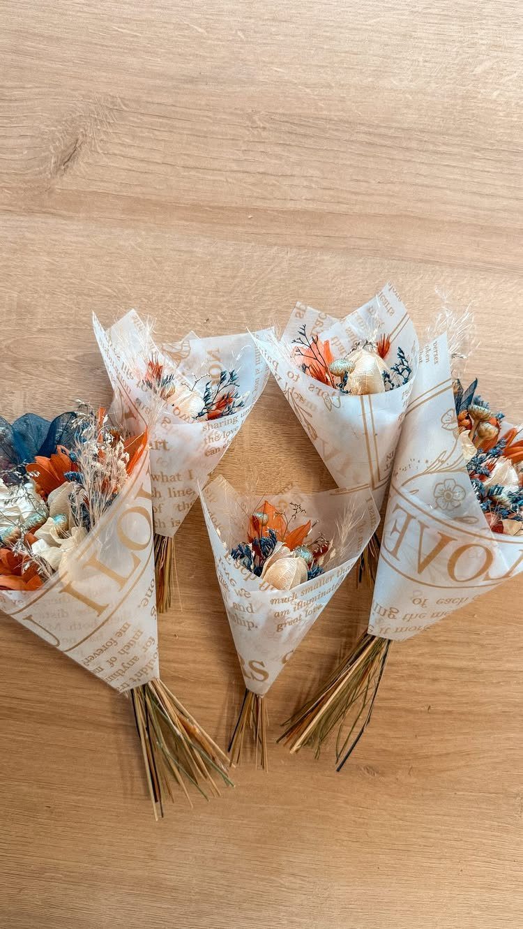 Mini dried flower bouquets wrapped in cream paper on a wooden table