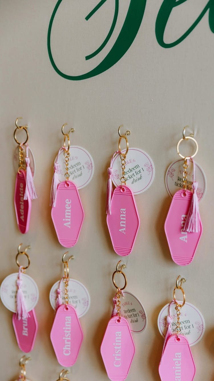 Pink acrylic personalized keychains with white names and tassels on white tags.