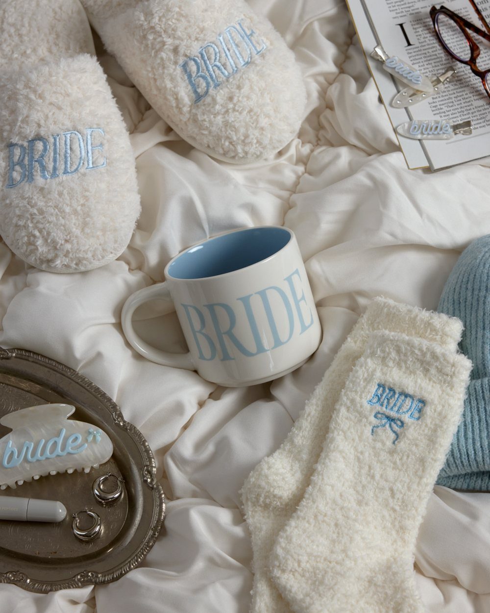 White fluffy socks and slippers embroidered with BRIDE on white fabric.