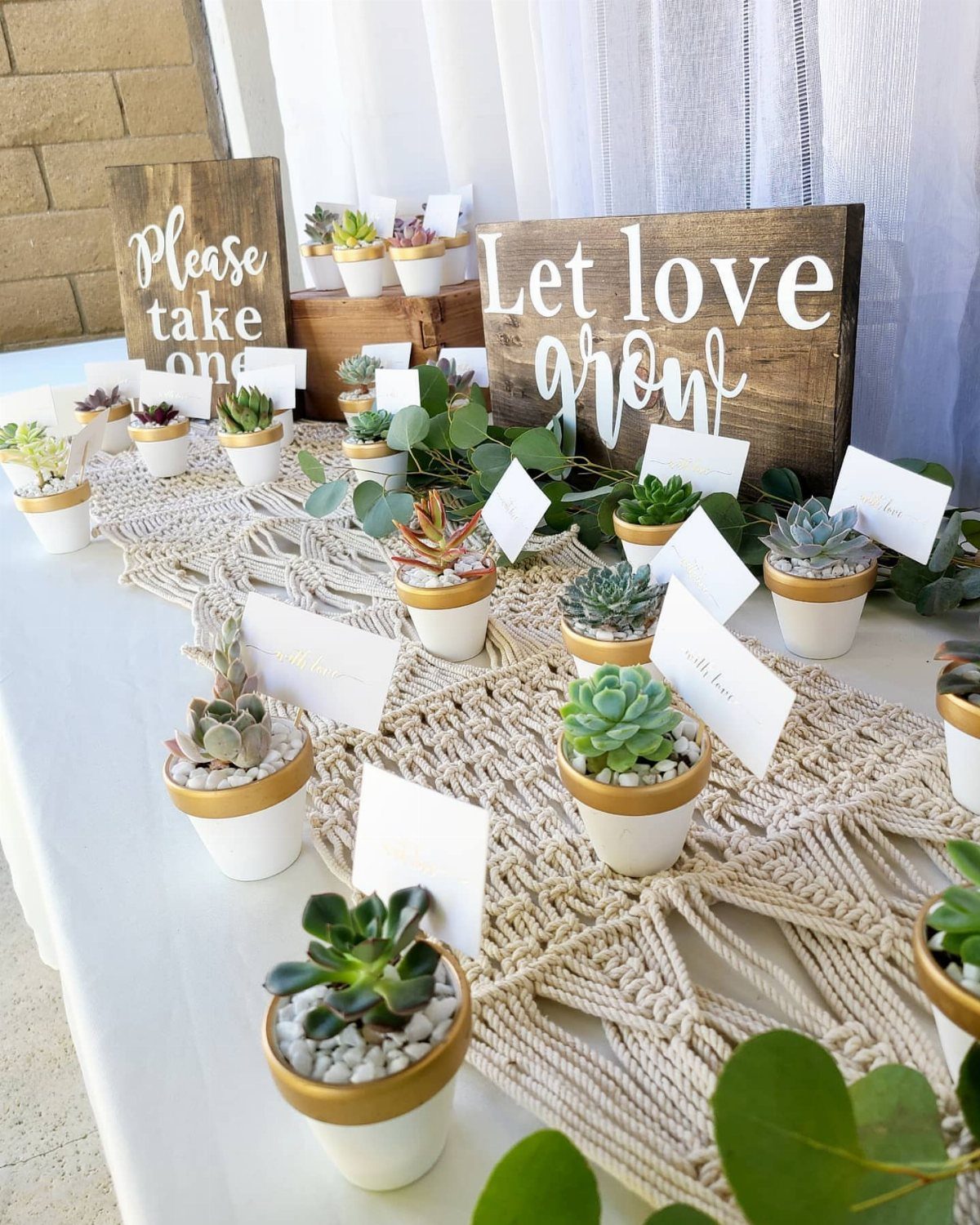 Small succulents in white and gold pots on a macrame table runner.