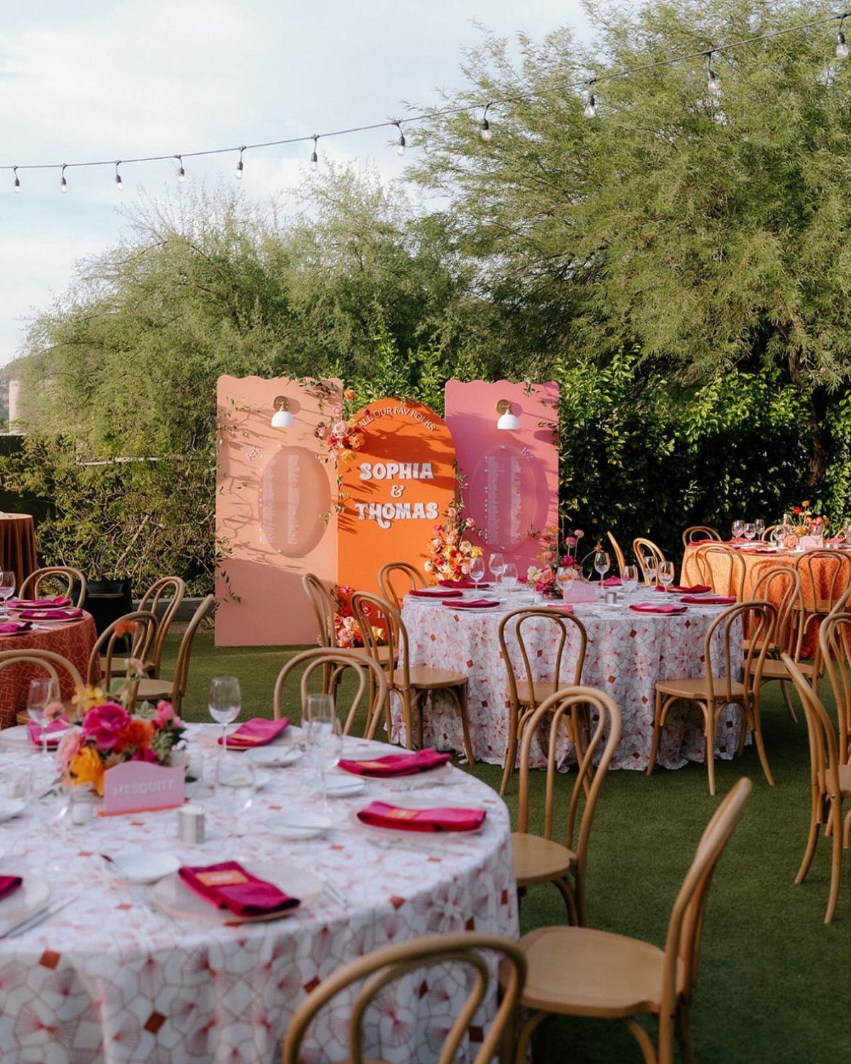 Pink and orange arched wedding signs with names Sophia and Thomas in outdoor setting