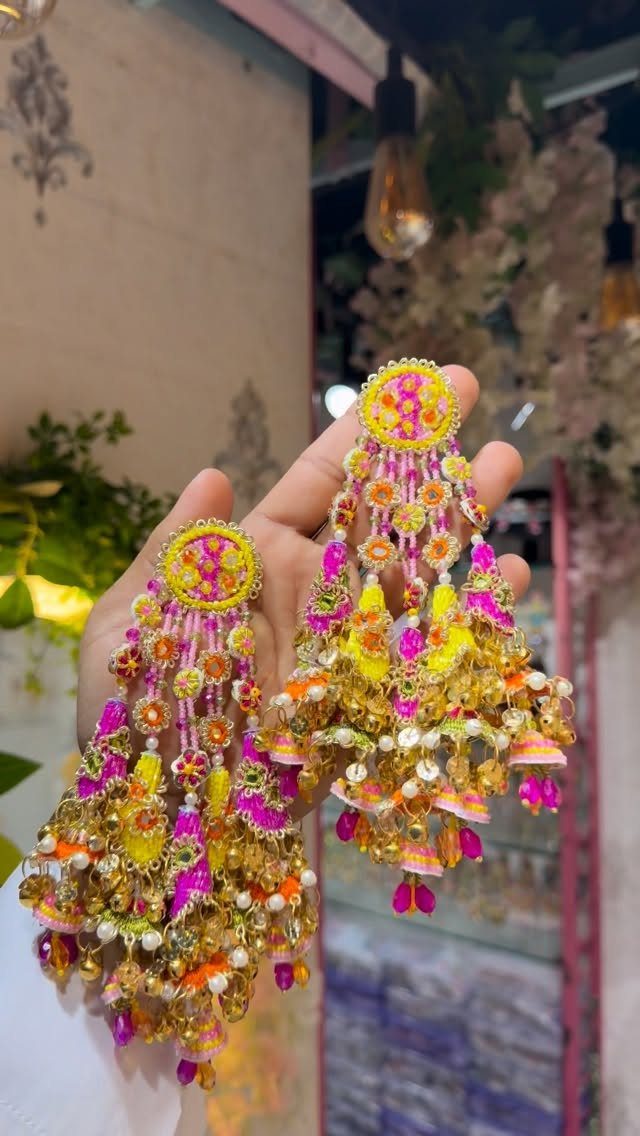 Ornate traditional earrings with bright pink and yellow beads and gold tassels.