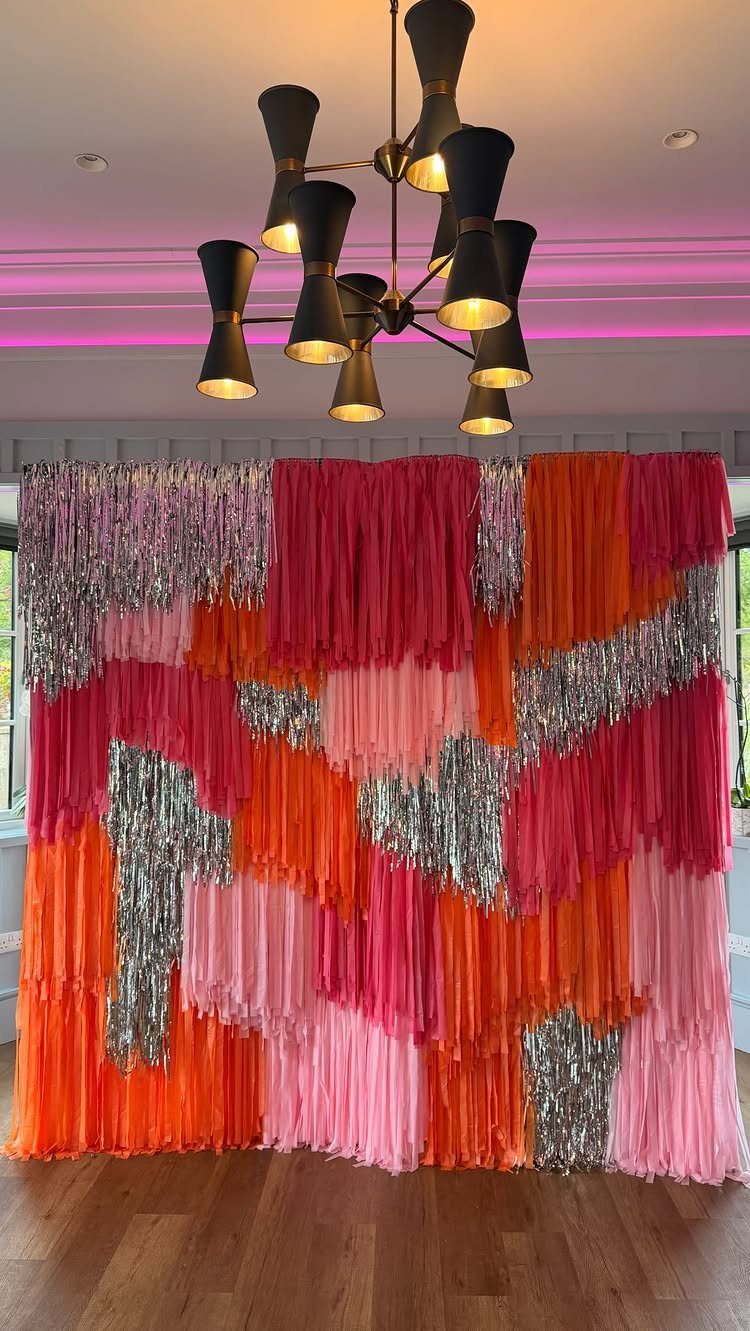 Vibrant pink, orange, and silver tinsel fringe backdrop in a modern room.
