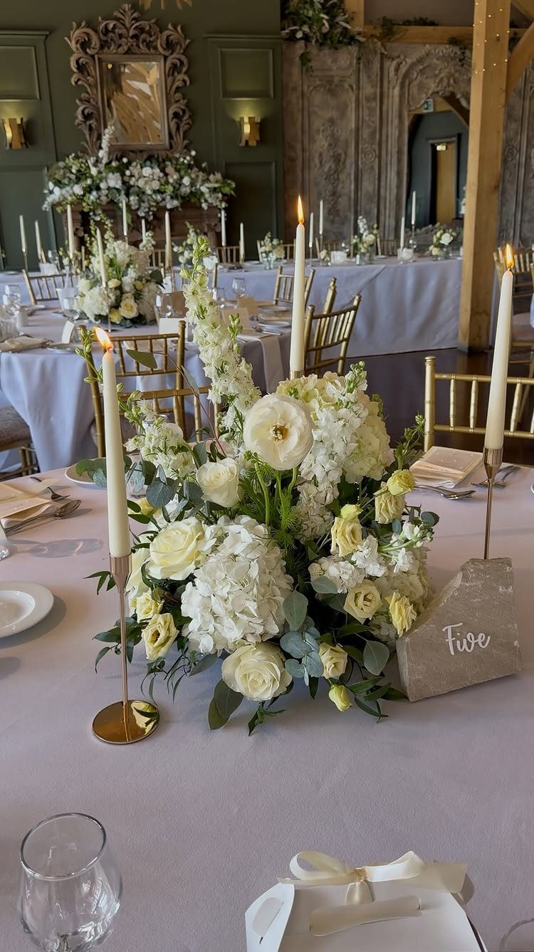 Butter yellow and white floral centerpiece with tall white taper candles on wedding table