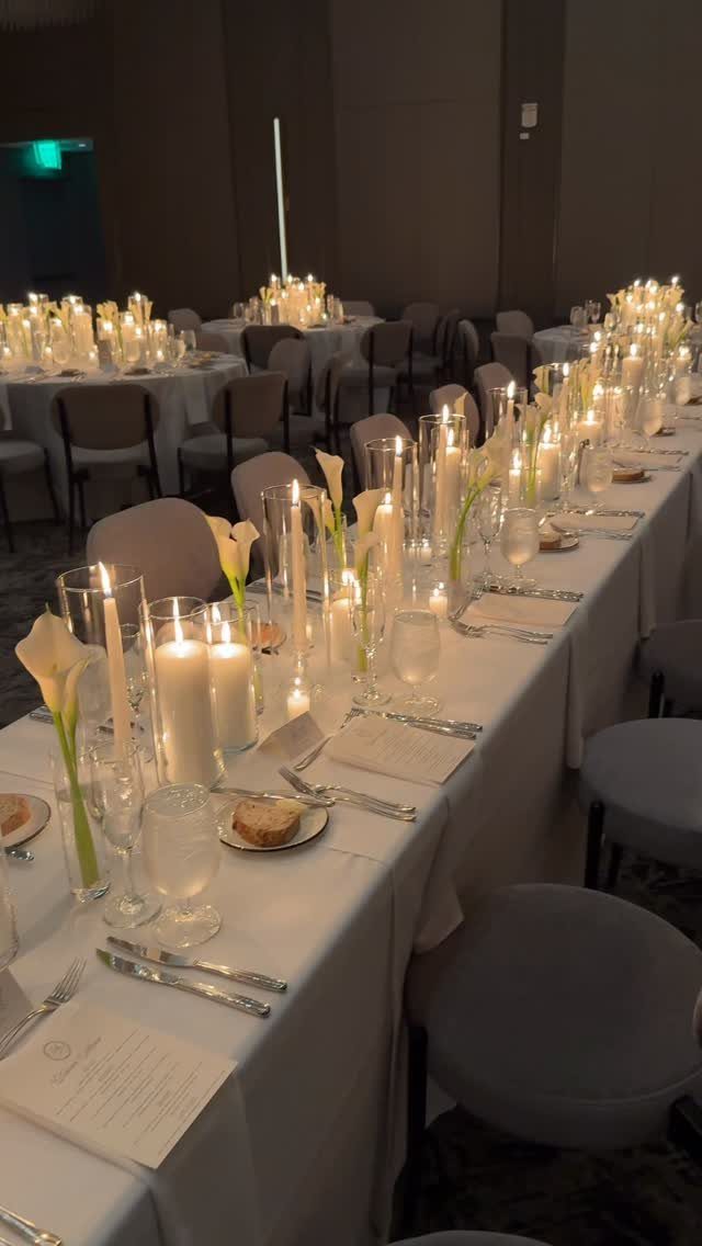 White calla lilies and pillar candles arranged as a low centerpiece on a wedding table