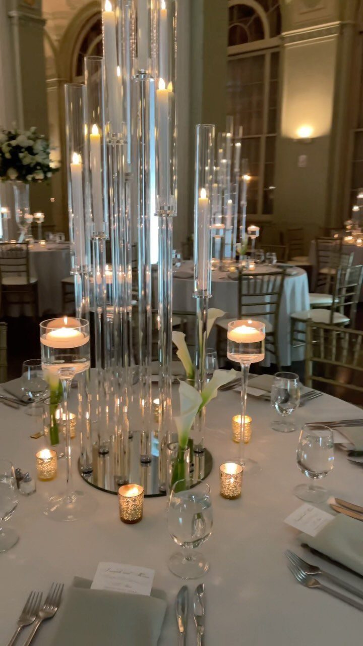 White calla lily centerpiece with tall glass cylinder candles on a wedding table.