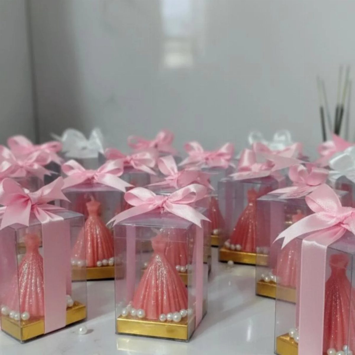 Pink gown shaped candles in clear gift boxes with pink satin bows.