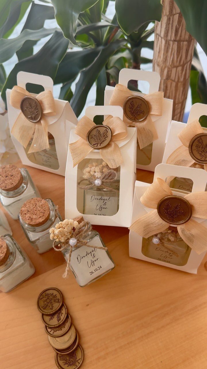 Small gift jars and boxes with gold bows and wax seals on wood.