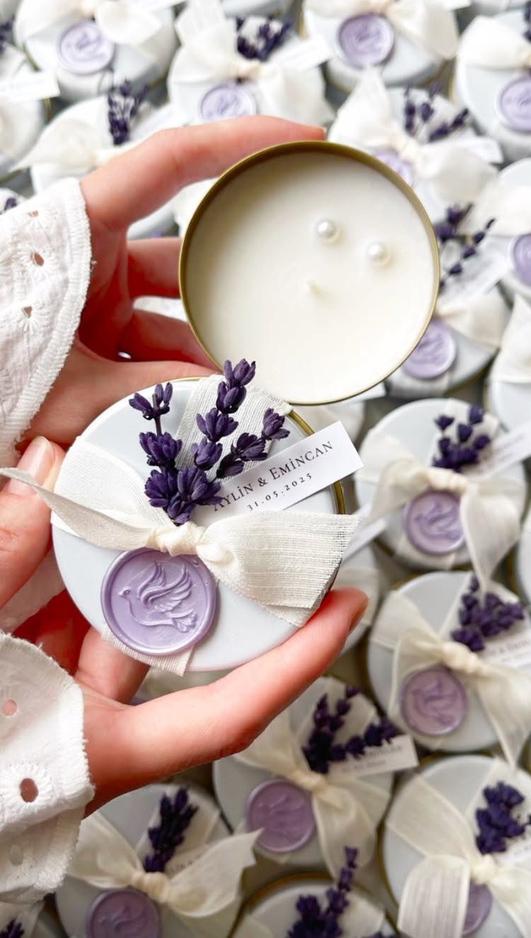 Small gold tin candles with lavender sprigs and purple wax seals for wedding gifts