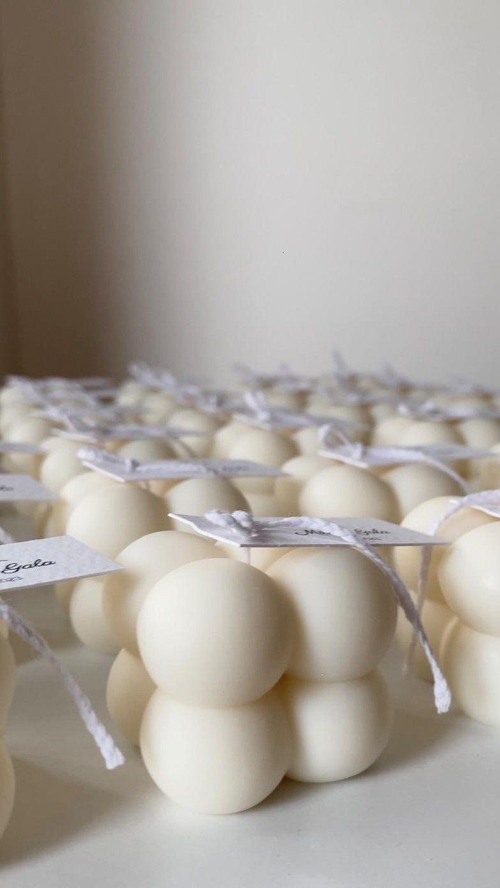 White bubble candles with small gift tags arranged in neat rows on white surface