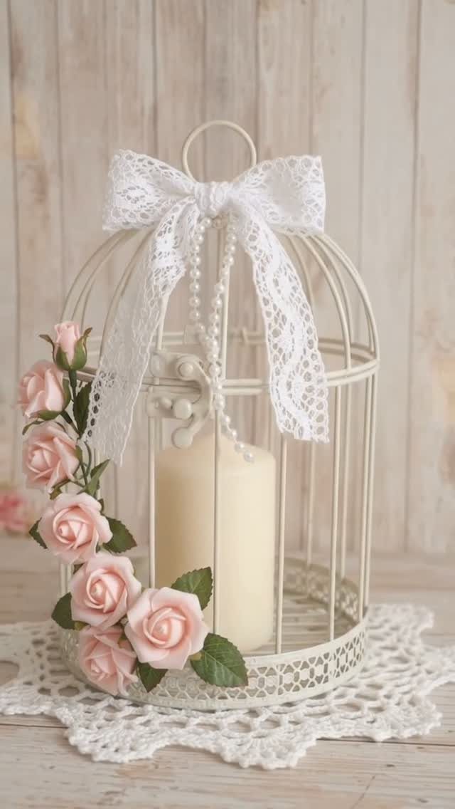 White decorative birdcage centerpiece with a cream candle, pink roses, and lace bow.