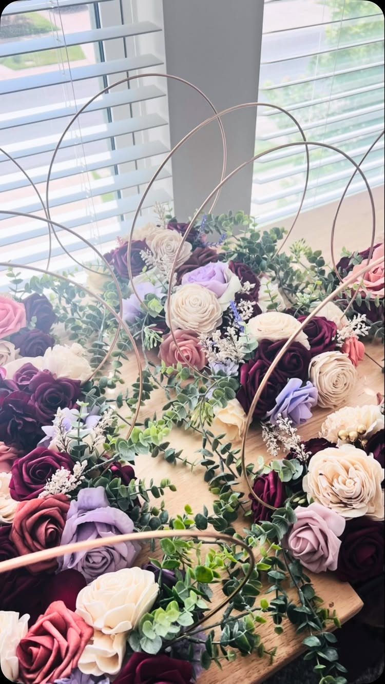Floral centerpieces with roses and eucalyptus inside gold circular hoops on wooden table