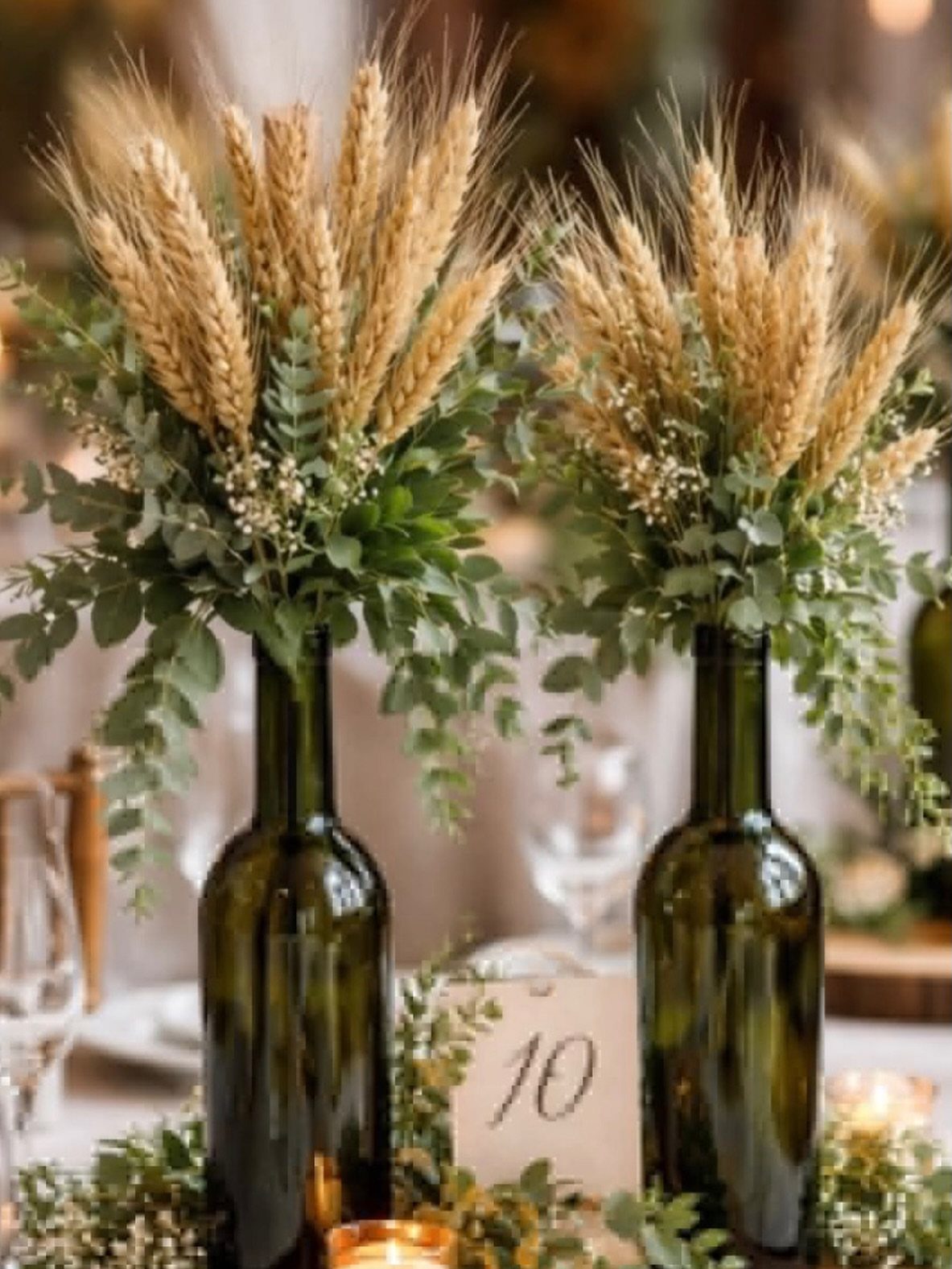 Green wine bottle centerpieces with dried wheat and eucalyptus on a wedding table