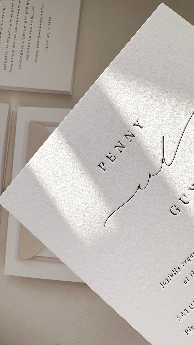 White textured wedding invitations with elegant black typography and minimalist design.