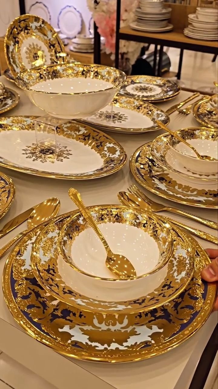 Ornate white and gold dinnerware set with blue accents and gold cutlery.