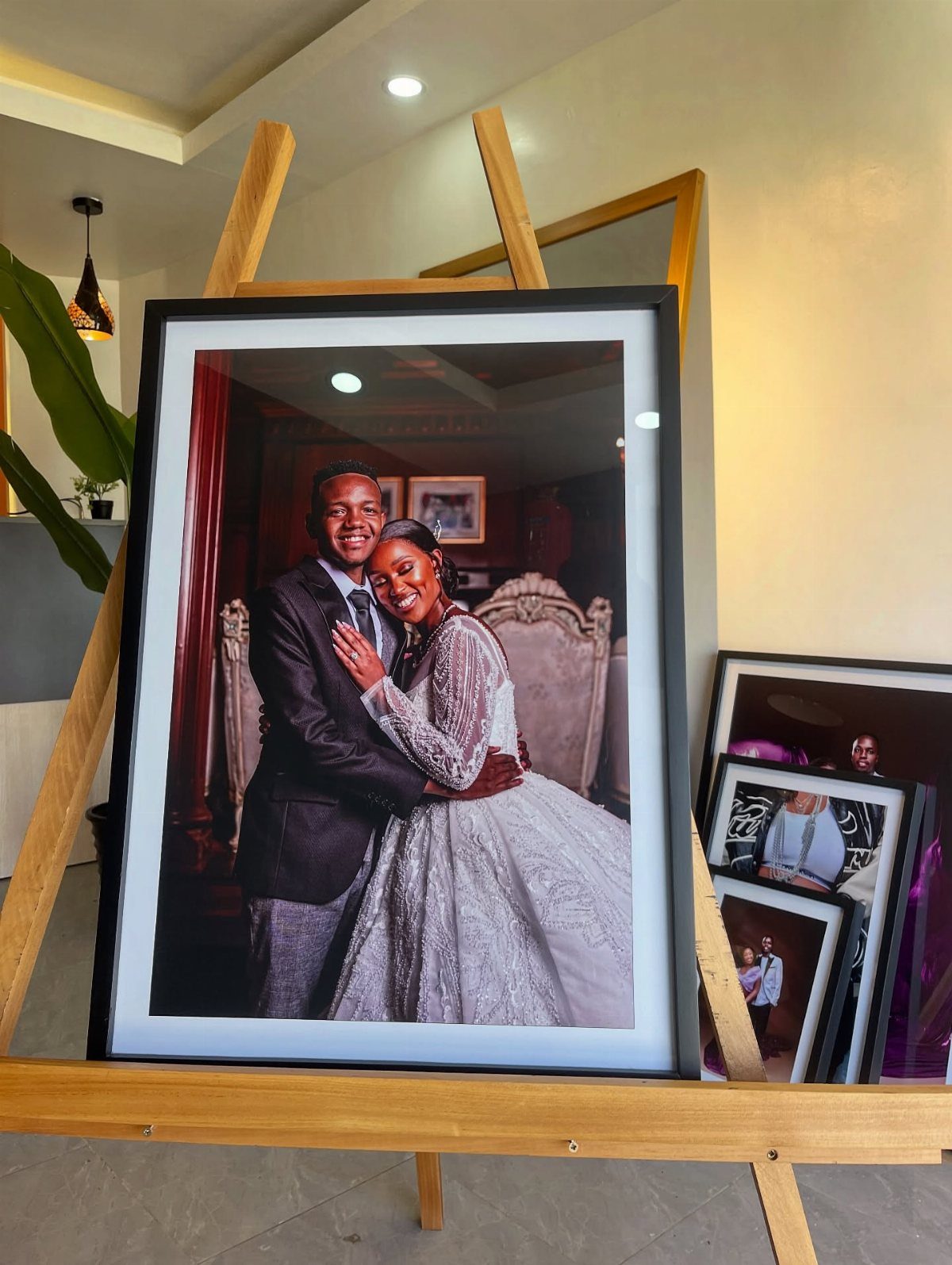 Black picture frame with wedding portrait displayed on a wooden easel indoors