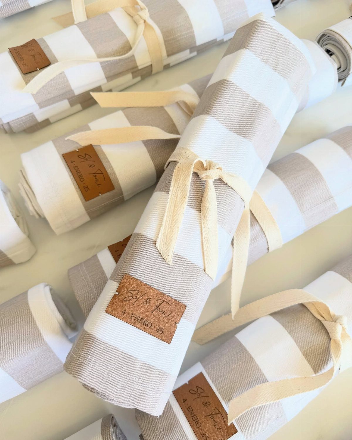 Rolled striped beach towels tied with ribbons and custom leather tags for guests.