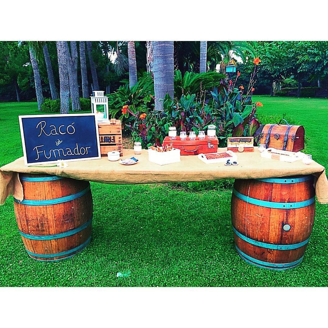 Cigar station with a burlap table on wooden barrels in a garden setting.