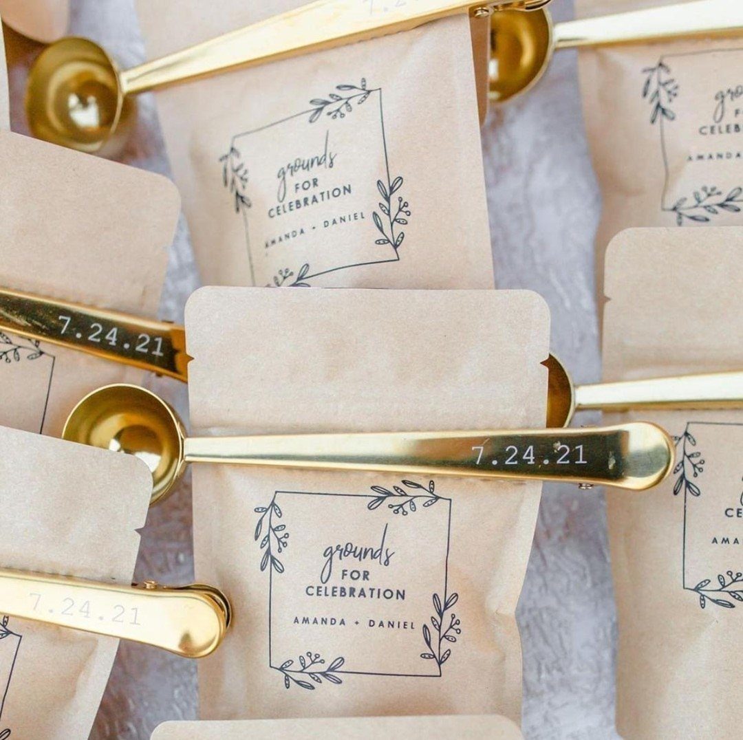 Brown kraft coffee bags with celebration labels and gold coffee scoops with dates.