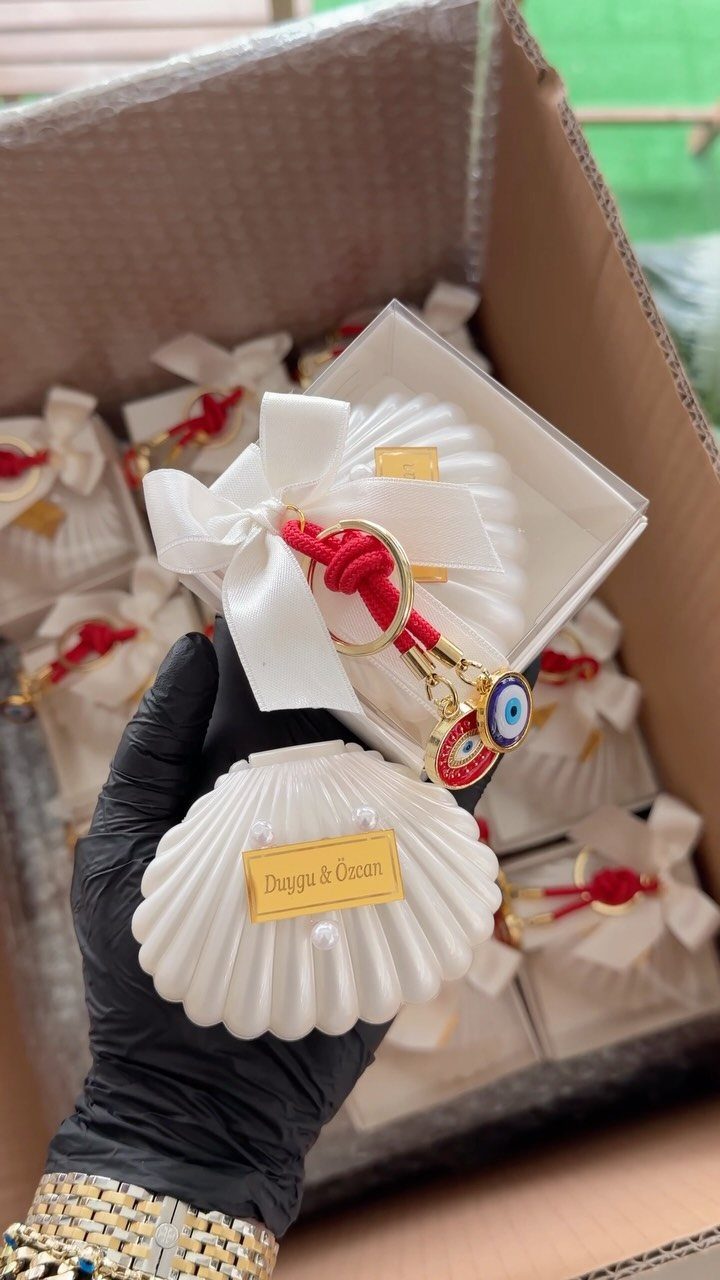 White seashell favor boxes with red wristlets and blue evil eye charms.