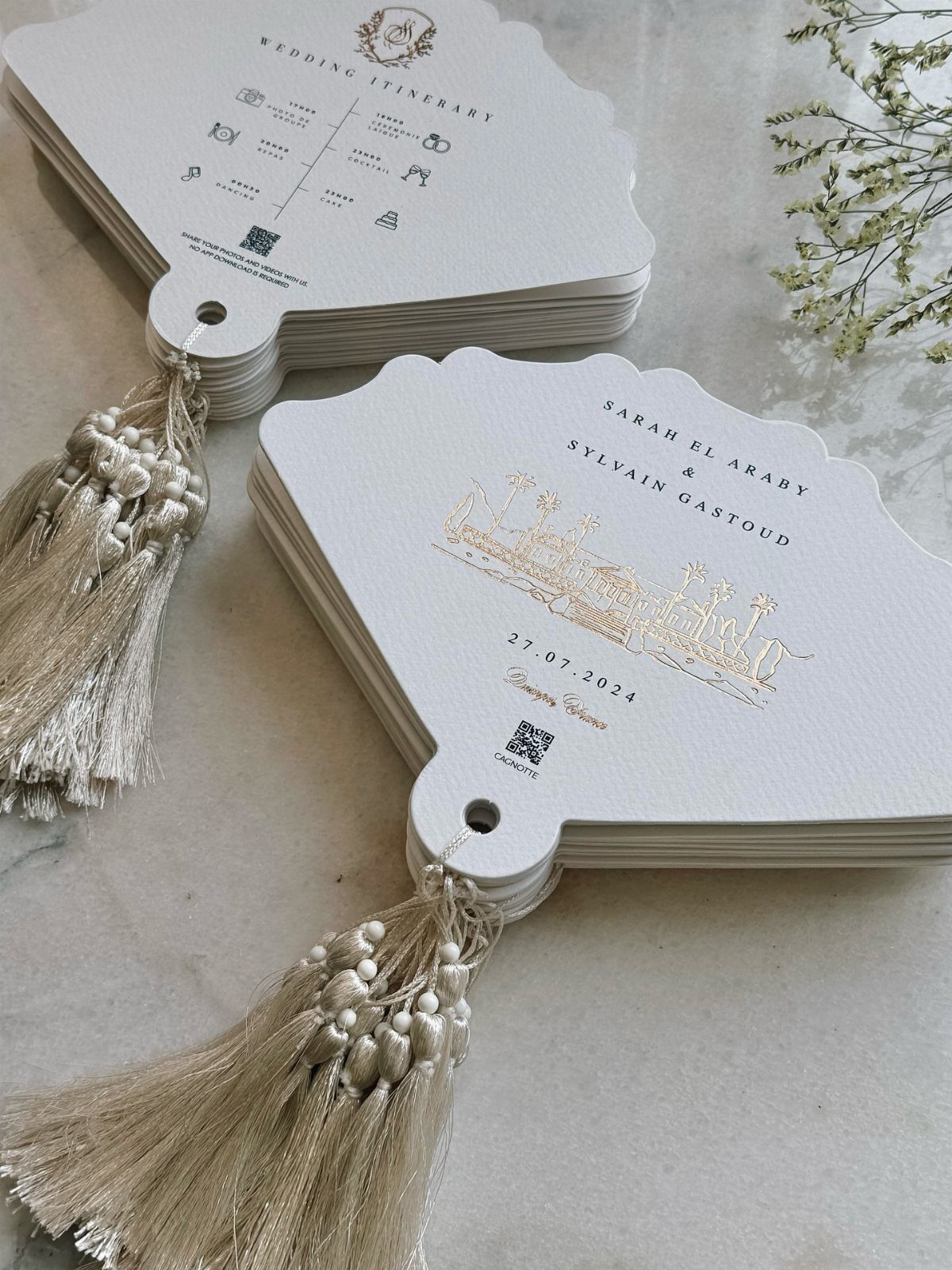 White scalloped wedding hand fans with gold foil lettering and gold tassels.