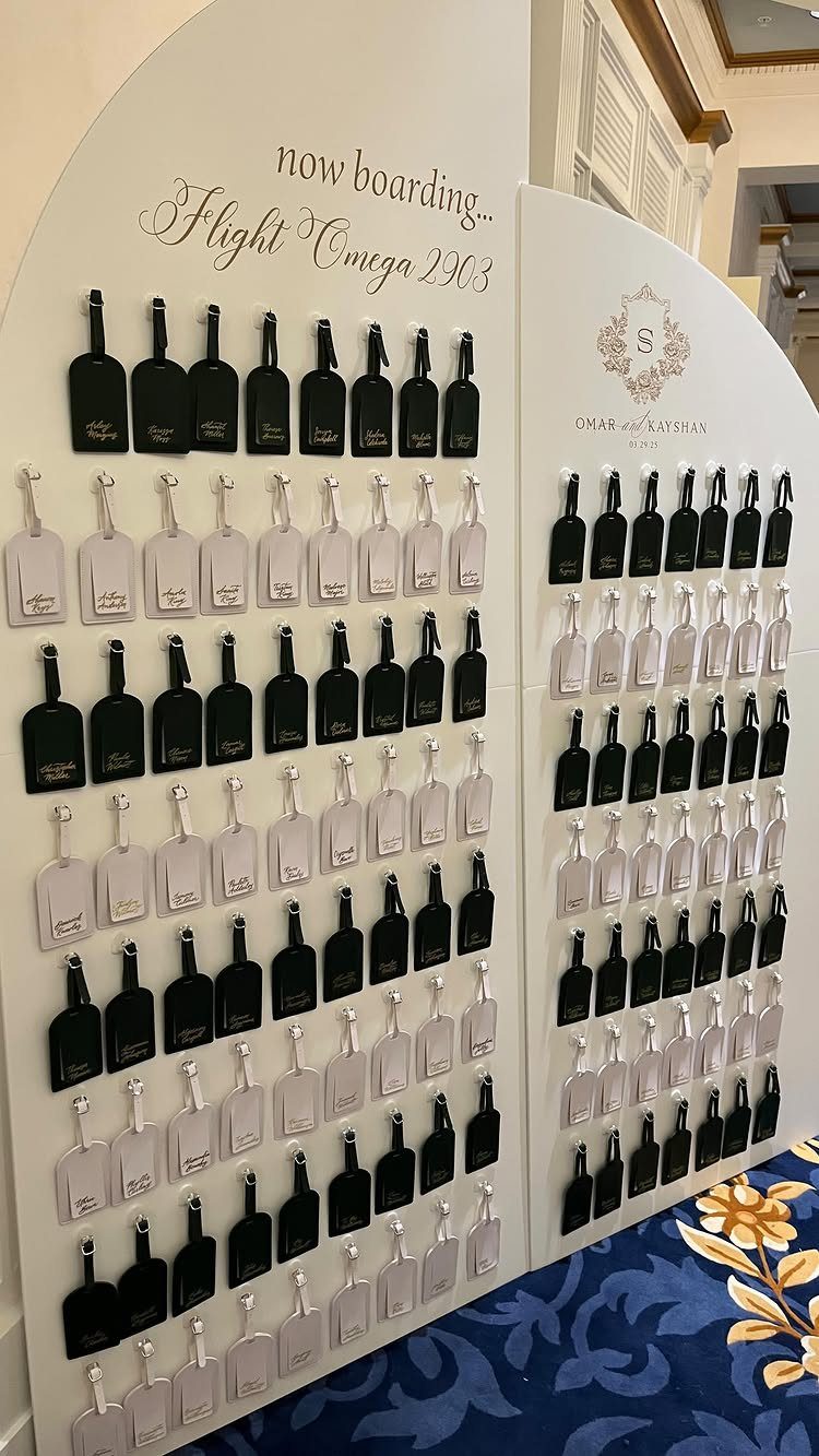 Black and white luggage tags displayed on a white wall for wedding guests.