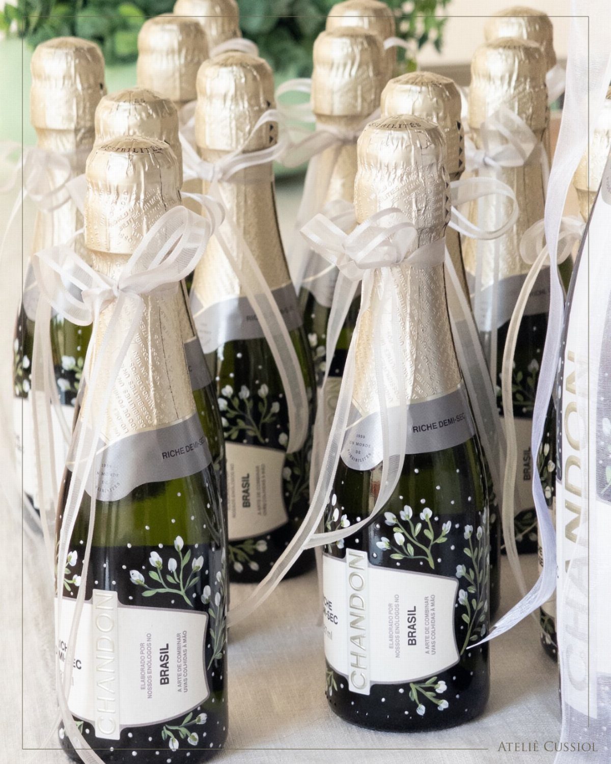 Mini champagne bottles with gold foil tops and white satin ribbon bows.