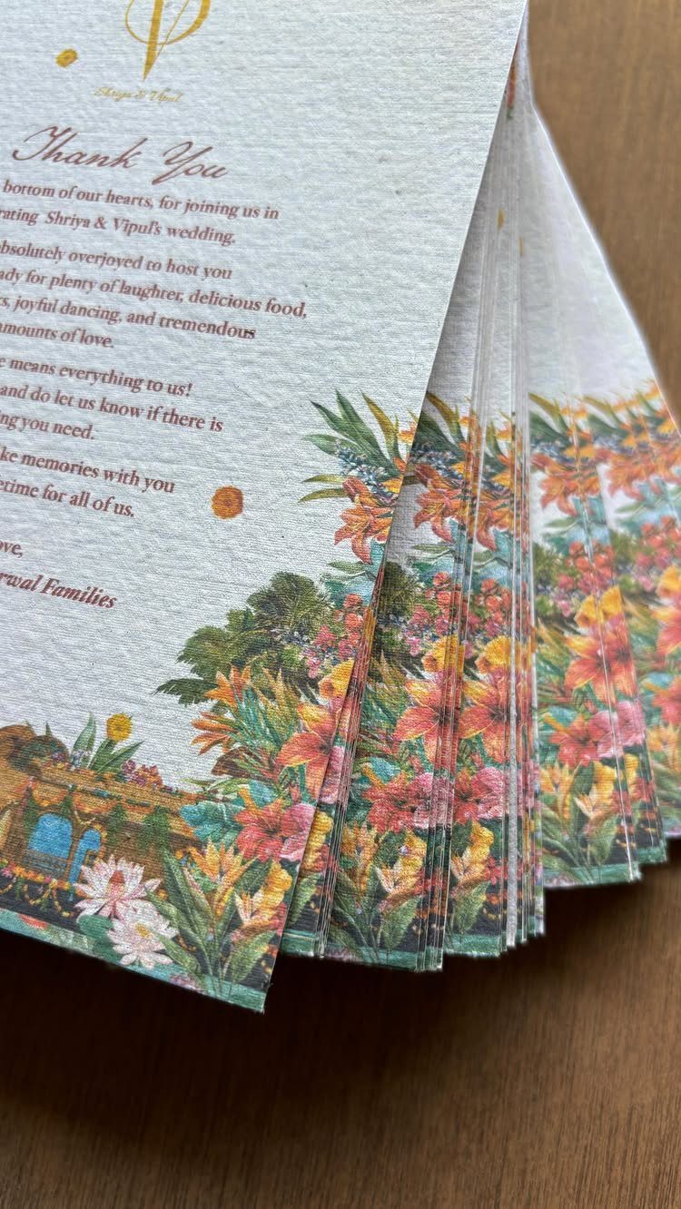 Stack of white textured thank you cards with colorful floral borders on wood.