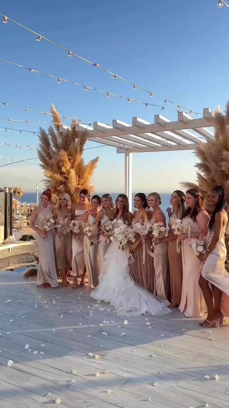 Bride and bridesmaids in gradient shades of champagne and beige dresses outdoors.