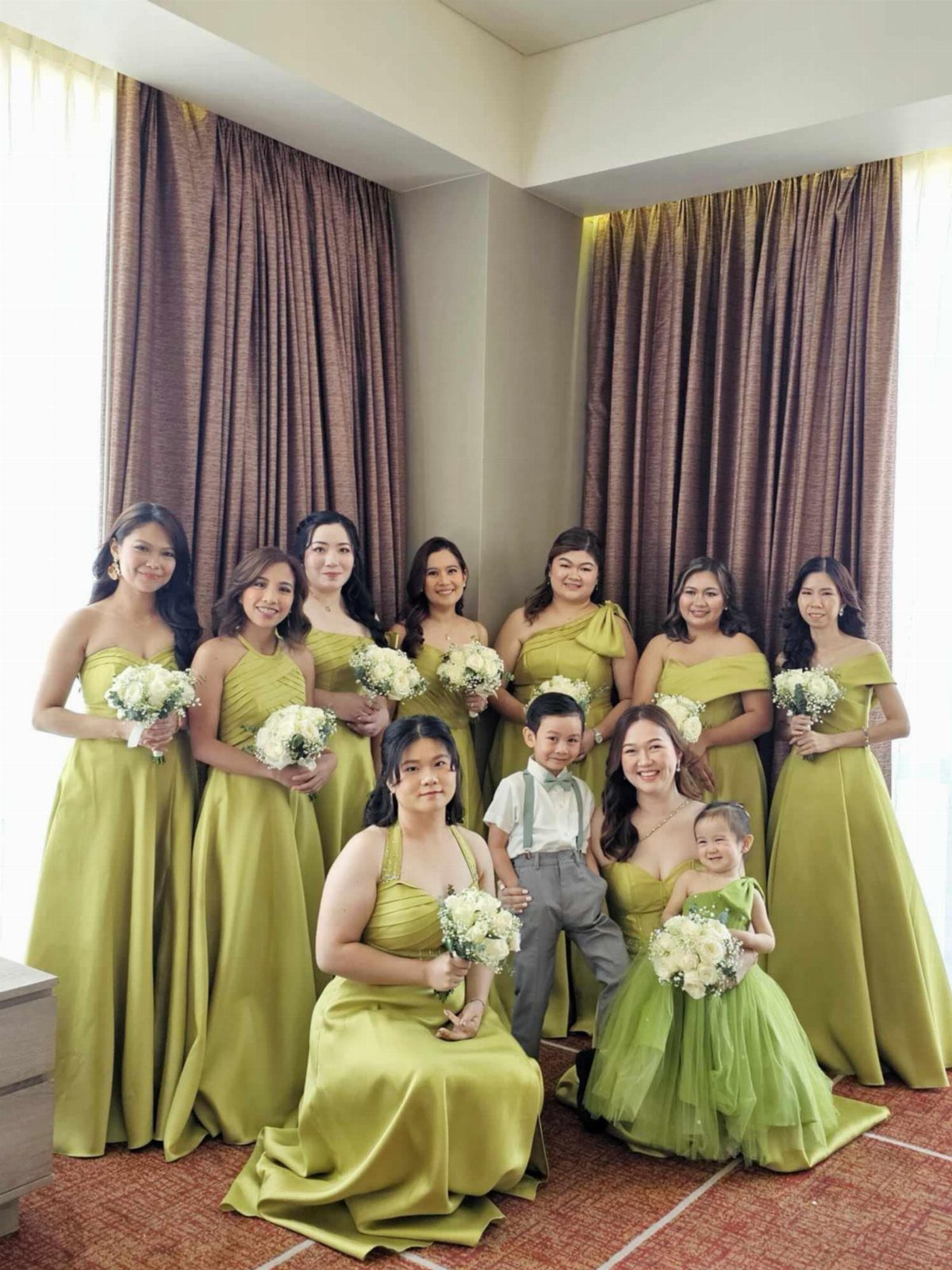 Bridesmaids in various styles of chartreuse green dresses holding white flower bouquets.
