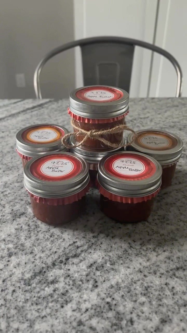 Small glass jars of homemade apple butter with labels on a granite counter