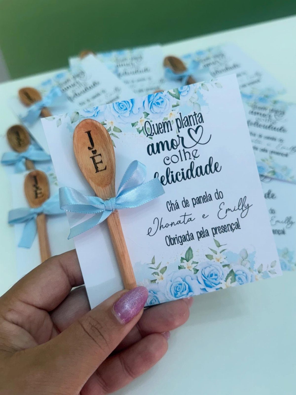 Wooden spoon with engraved letter attached to a floral bridal shower card.