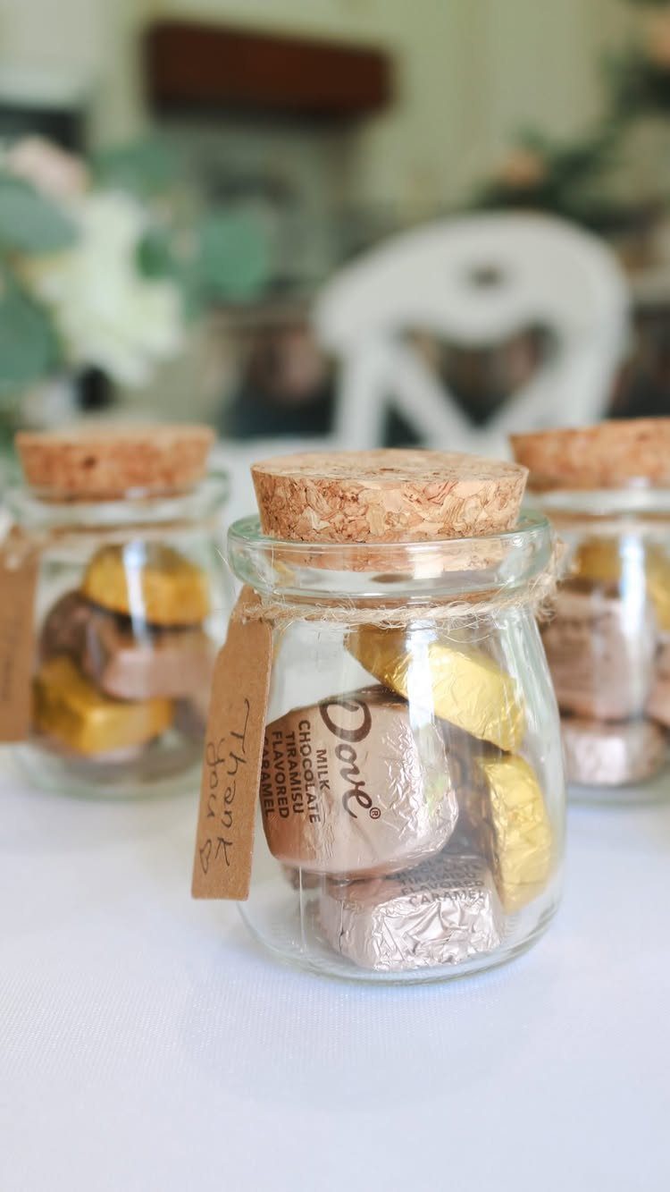 Small glass jars with cork lids filled with wrapped chocolates and kraft tags.