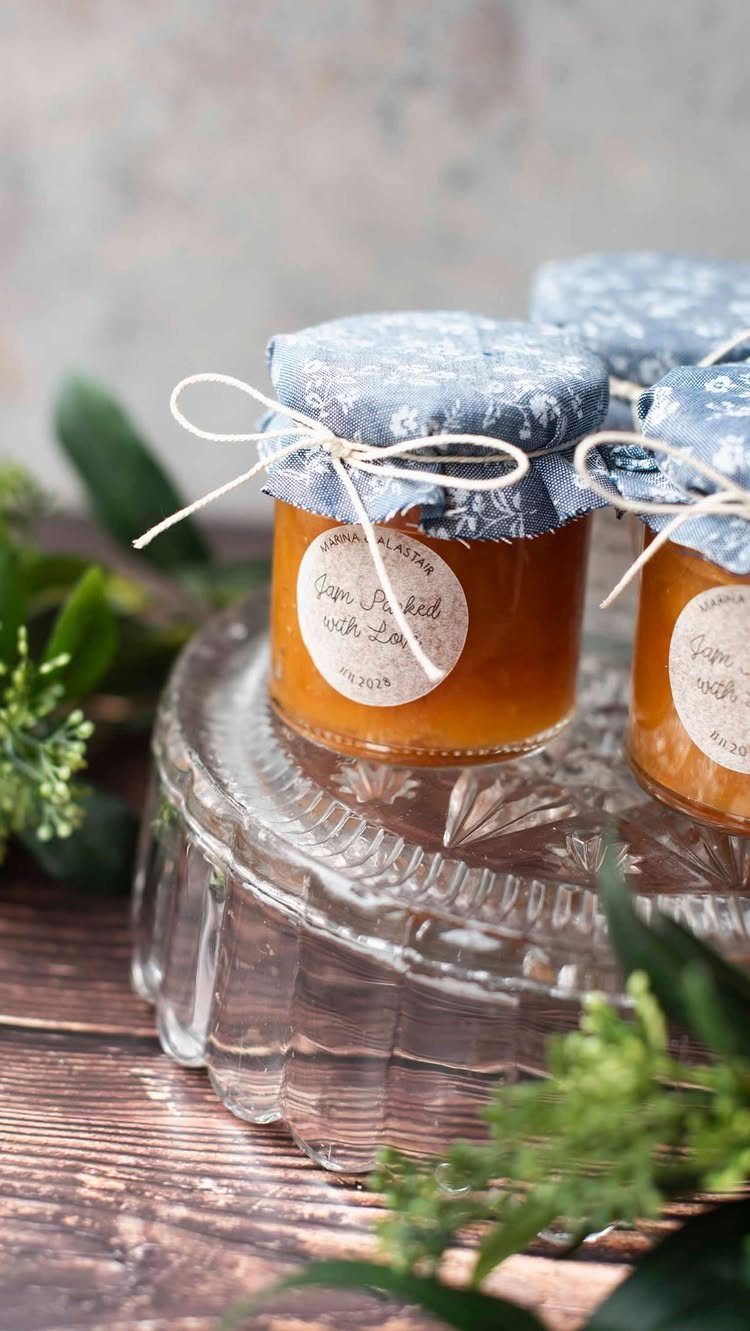 Small jars of orange jam with fabric lids and twine on glass pedestal