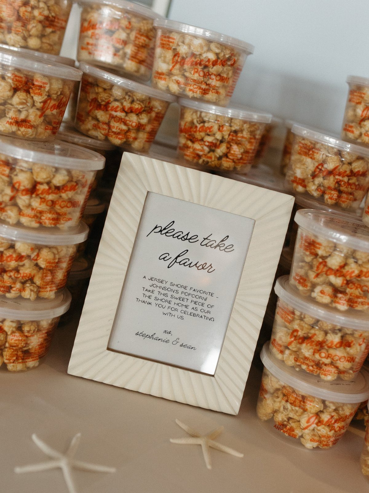 Clear plastic jars filled with orange popcorn next to a favor sign and starfish.