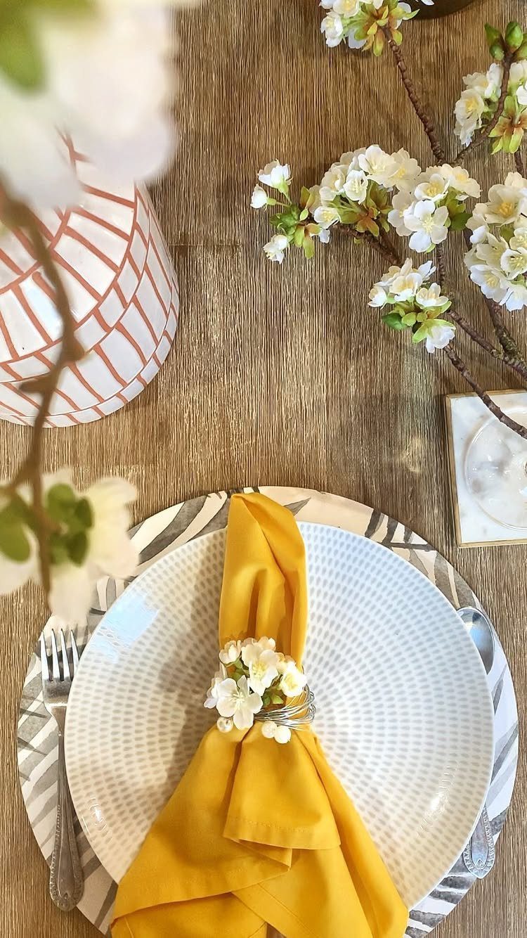 Yellow fabric napkin with a white floral napkin ring on a white plate.